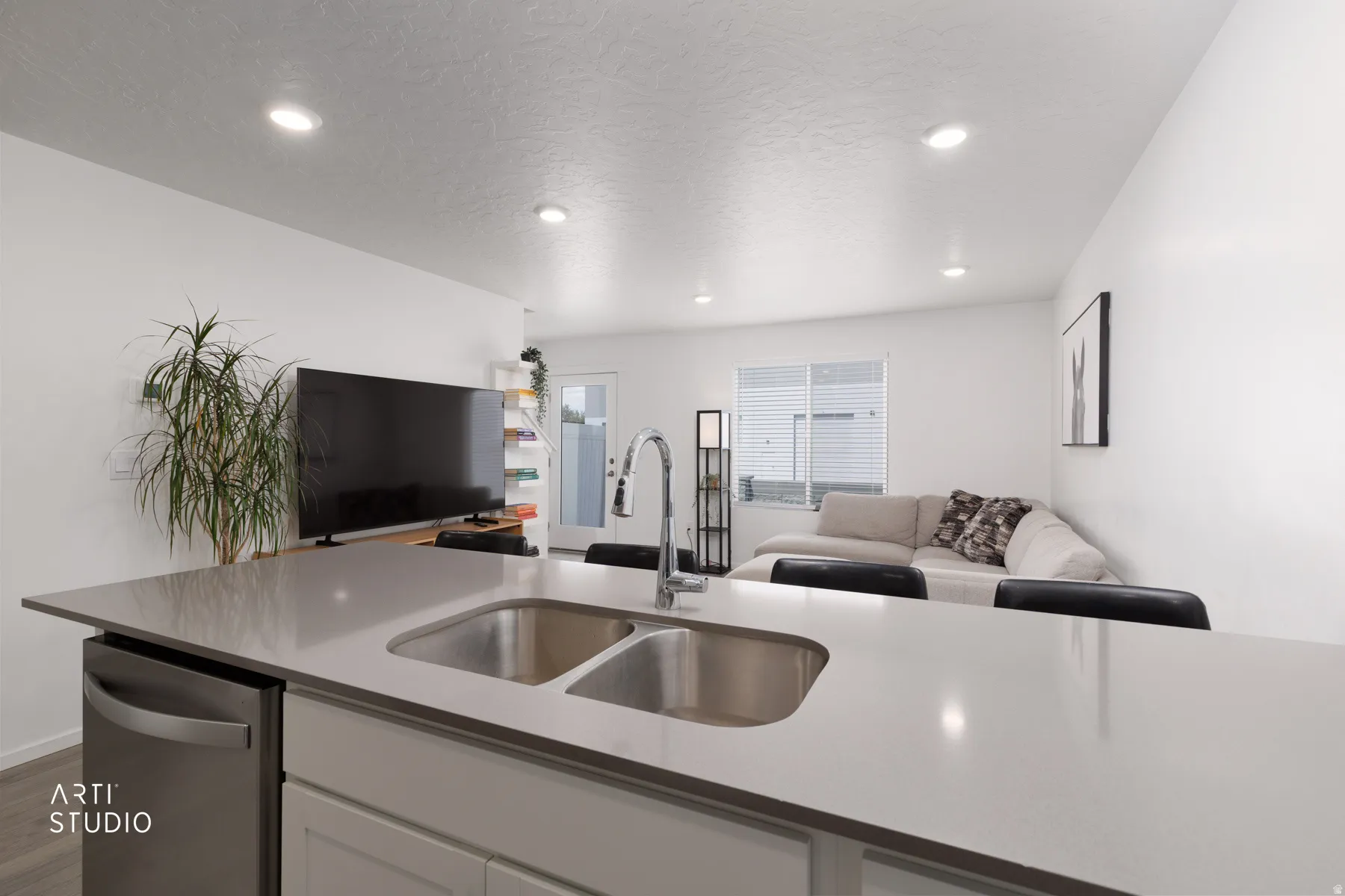 Kitchen island featuring a double basin stainless steel sink and a stainless steel dishwasher, with recessed lighting throughout