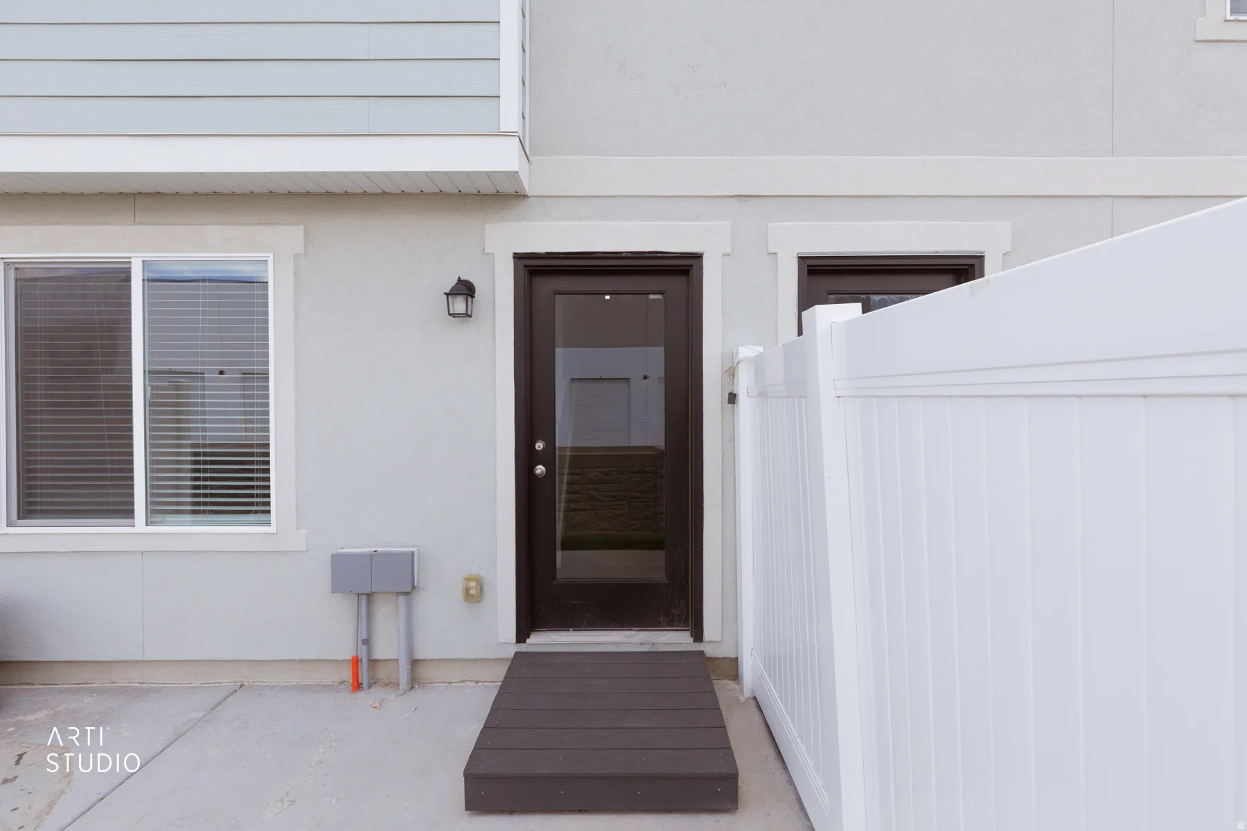 Private patio area featuring a white vinyl fence and a dark wood-finish ramp leading to an entry door