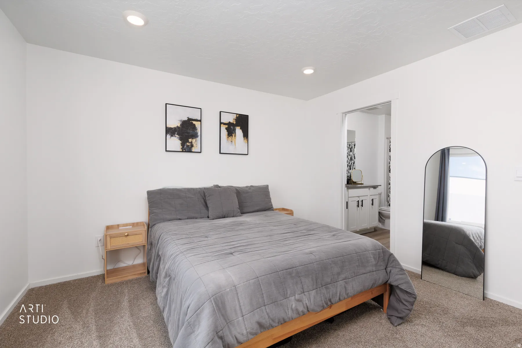 Recessed lighting, light-toned carpeting, and a doorway leading to a bathroom