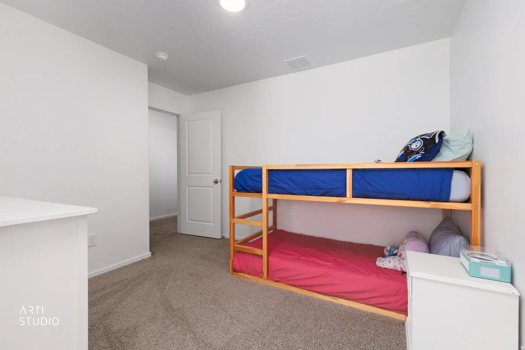 Plush carpet flooring, white painted walls, white interior door, recessed ceiling light, and a smoke detector