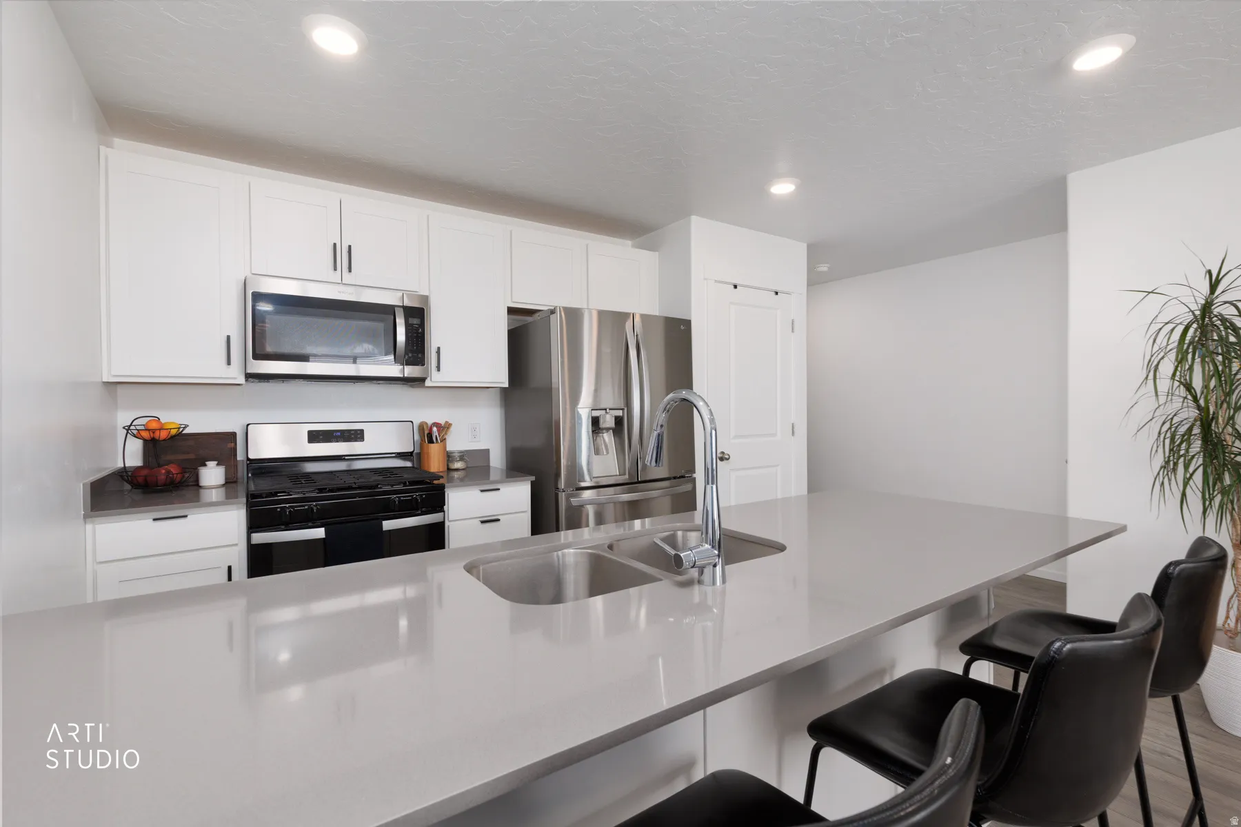 Kitchen featuring white cabinetry, stainless steel appliances, a large island with an integrated sink, and recessed lighting