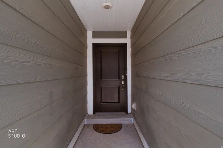 Entryway featuring a dark paneled door, white trim, and light-toned siding