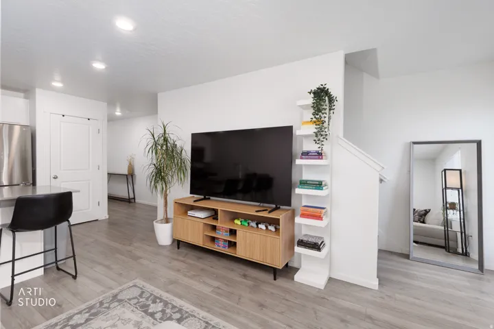 Recessed lighting, wood-finish flooring, stainless steel refrigerator, white interior walls, and built-in shelving