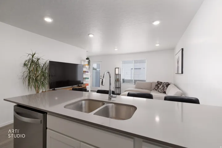 Kitchen island featuring a double basin stainless steel sink and a stainless steel dishwasher, with recessed lighting throughout