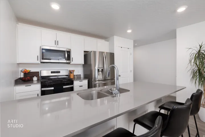 Kitchen featuring white cabinetry, stainless steel appliances, a large island with an integrated sink, and recessed lighting
