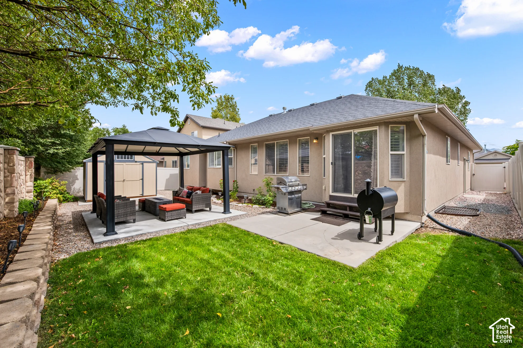 Expansive backyard featuring a manicured lawn, concrete patio, and an integrated gazebo
