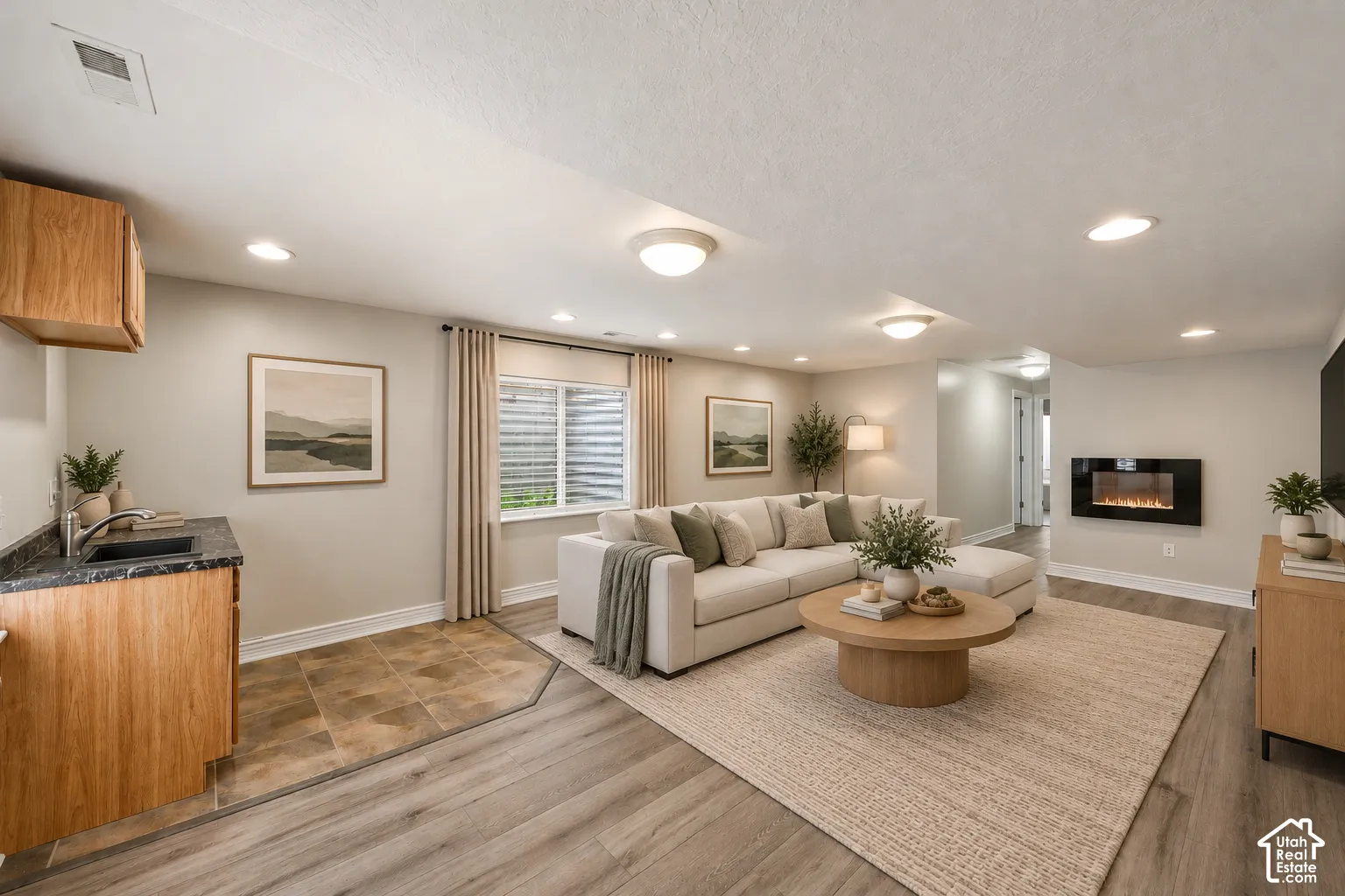 Living area featuring wood-finish flooring, a wall-mounted electric fireplace, and a built-in wet bar with a dark stone-finish countertop and sink