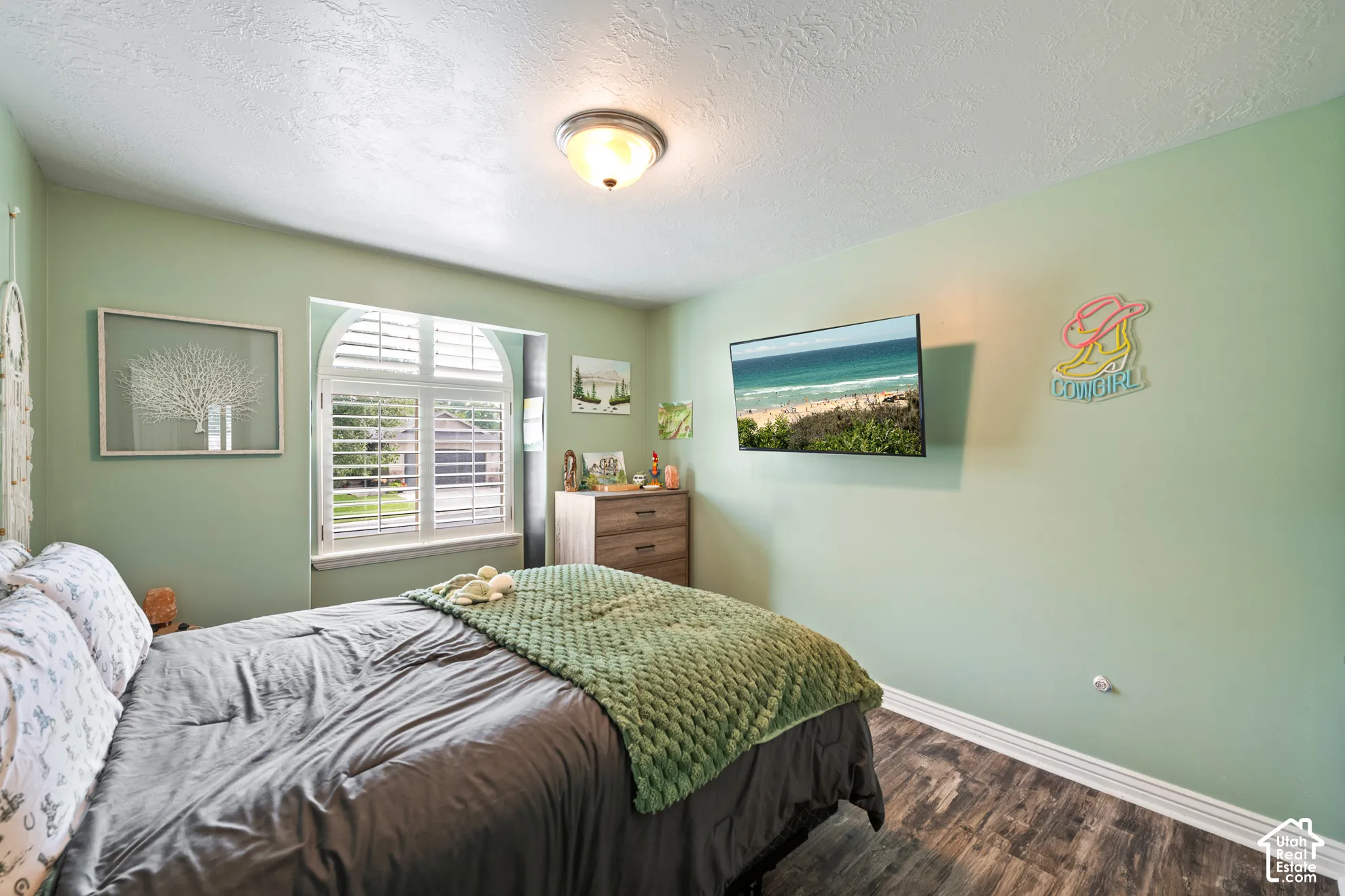 Arched window with plantation shutters, wood-finish flooring, flush mount ceiling light, and light green painted walls
