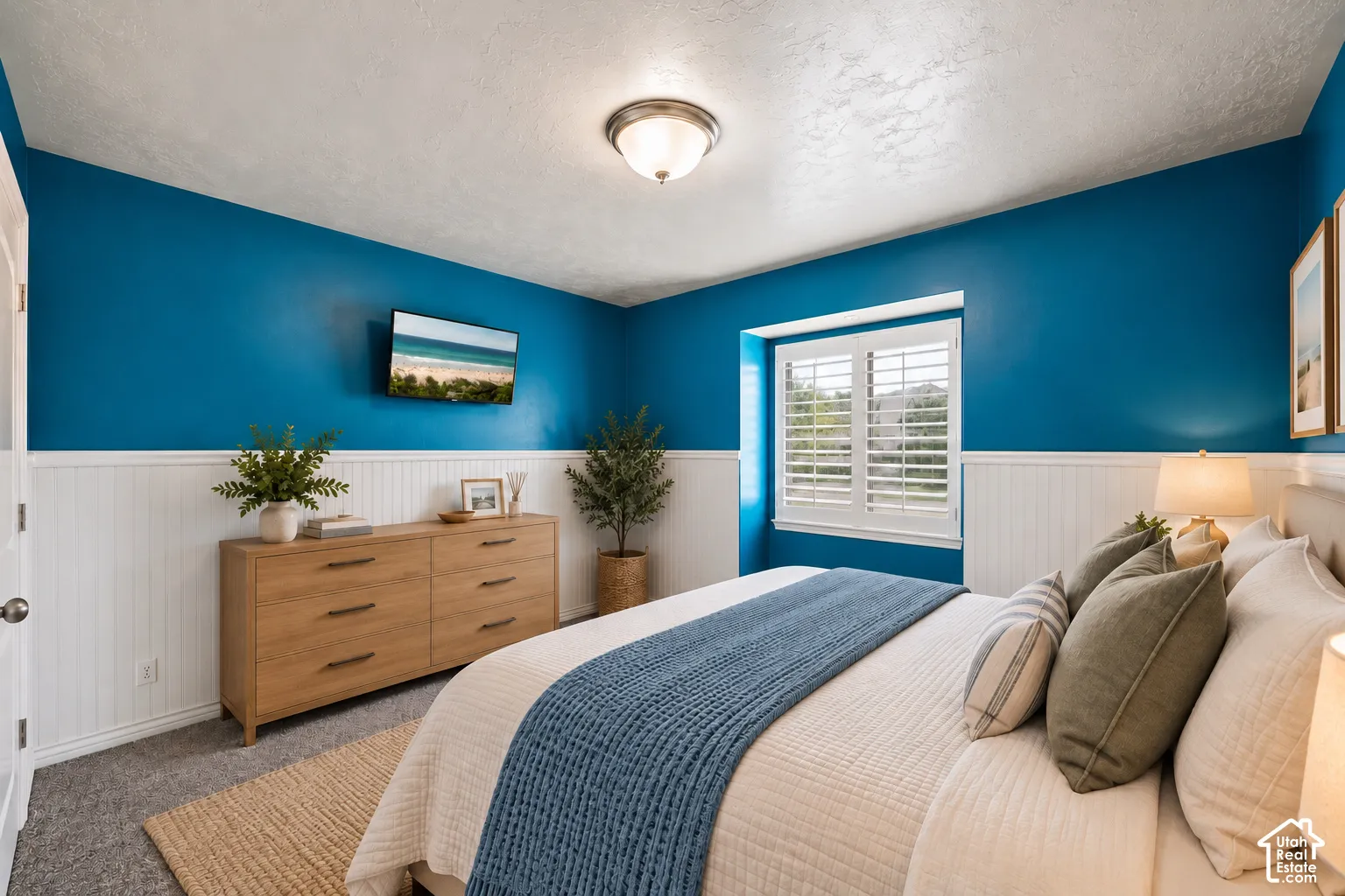 Interior space featuring white beadboard wainscoting, a double-hung window with plantation shutters, neutral-tone carpeting, and a flush-mount ceiling light fixture
