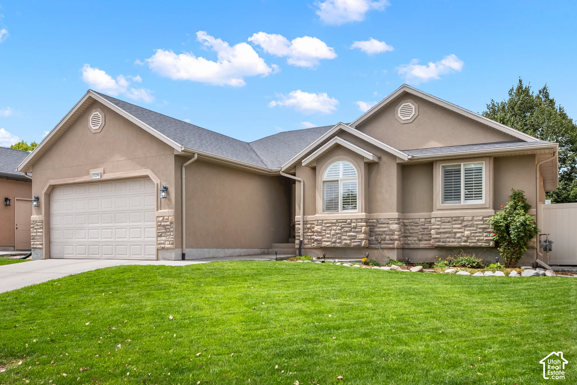 Stucco exterior with stone accent detailing, arched window, and attached garage