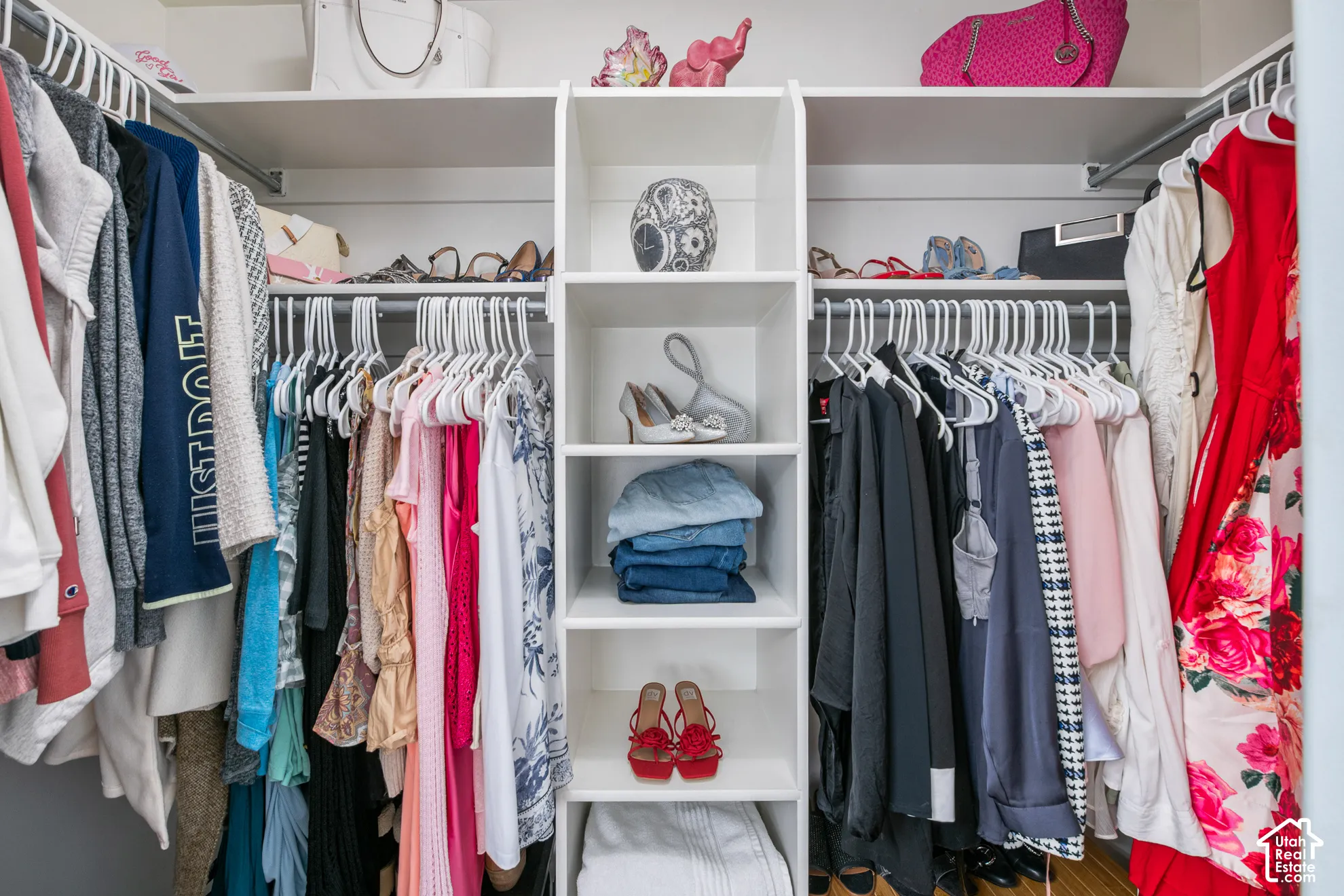 Built-in white storage system featuring multiple hanging rods, shelving, and cubbies
