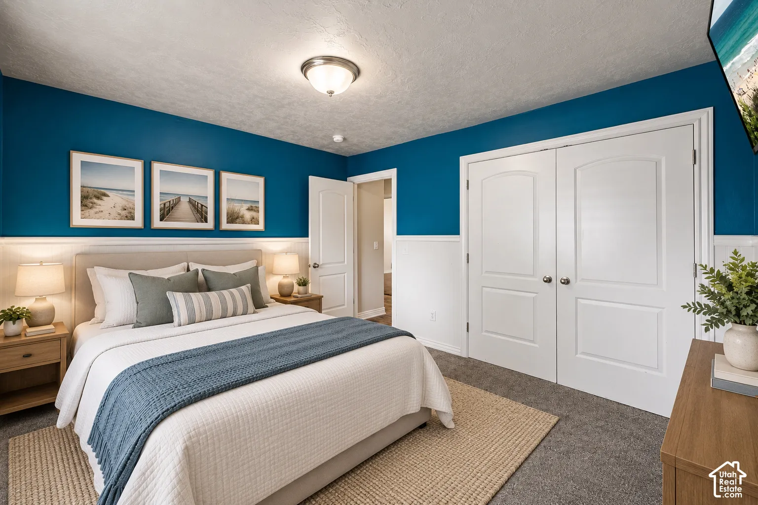 Bedroom featuring two-tone wall treatments with crisp white wainscoting, white arched-panel double closet doors, matching white interior doors, and neutral carpeting