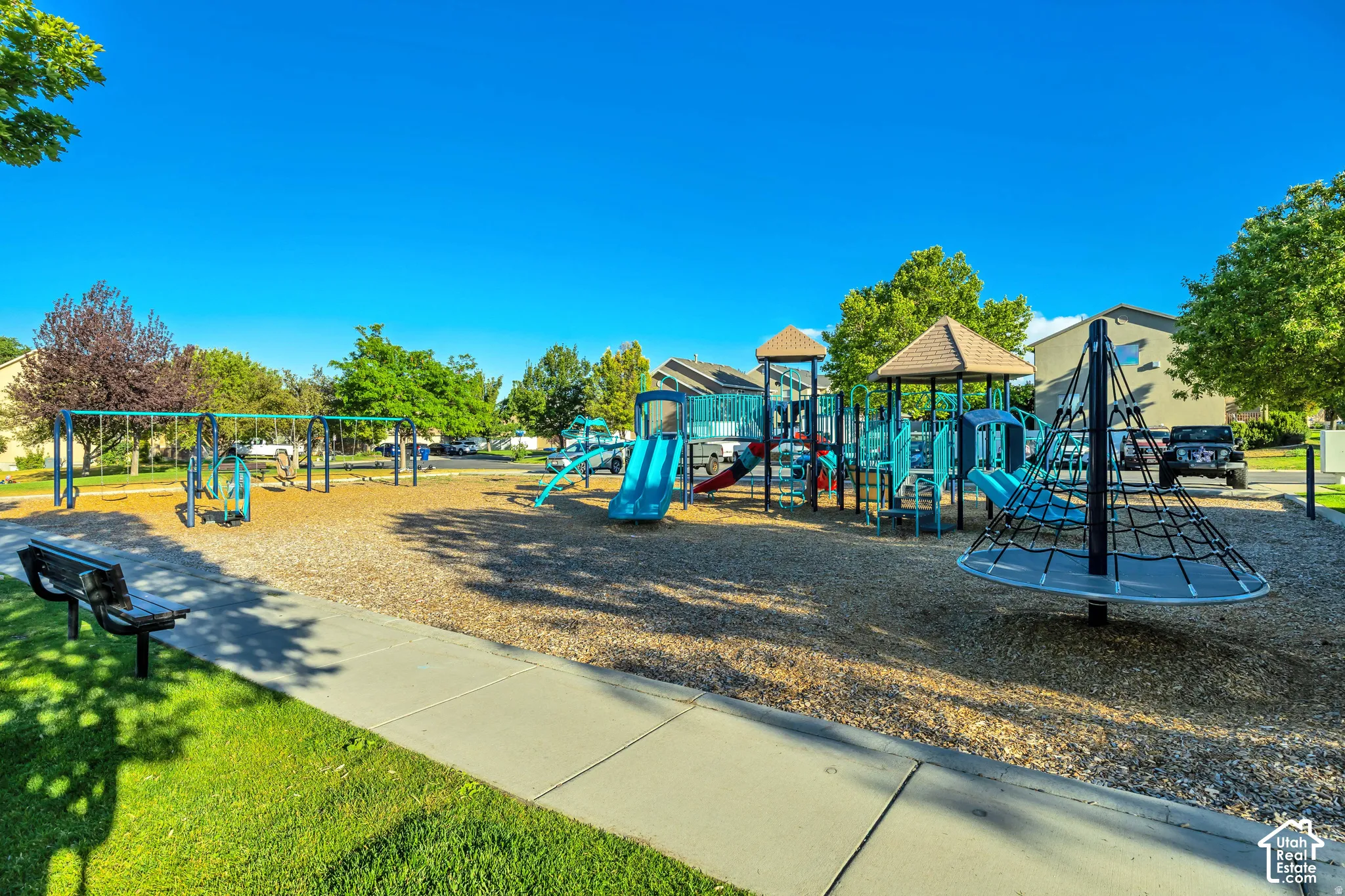 Community playground featuring multiple slides, swing sets, a climbing structure, and a wood chip surface