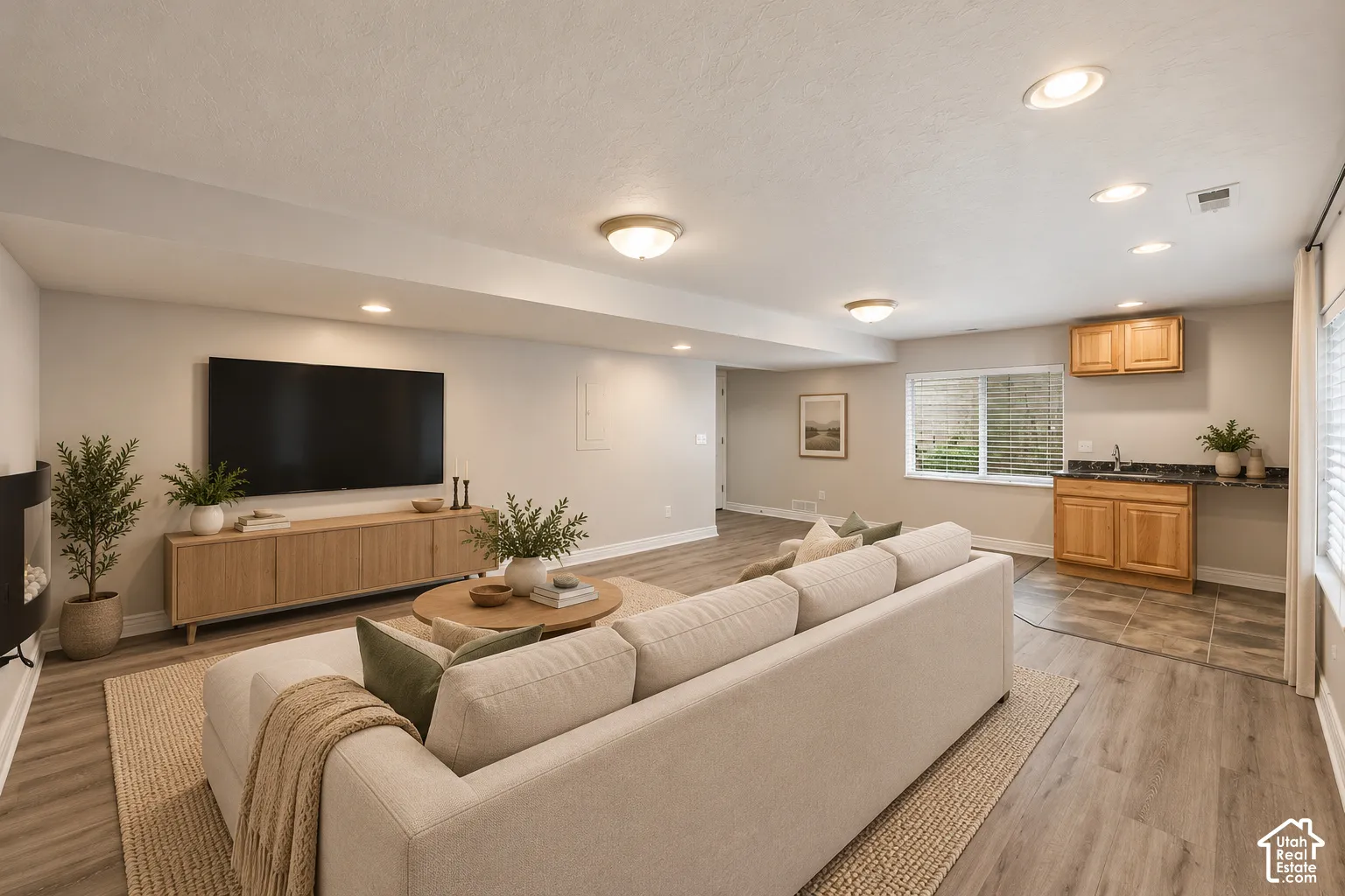 Open-concept space featuring wood-finish flooring, recessed lighting, a built-in wet bar with cabinetry, and a wall-mounted fireplace