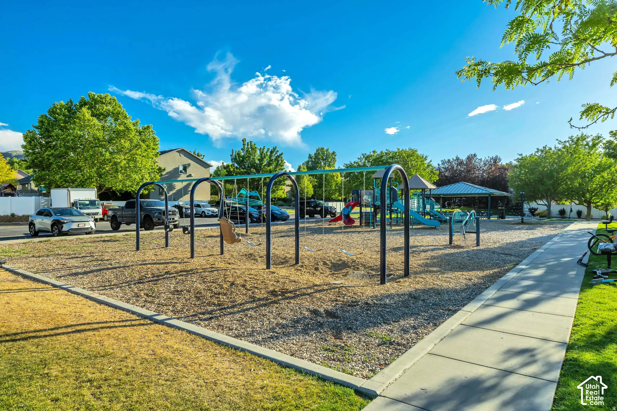 Recreational area featuring a swing set, playground equipment, and covered shelter