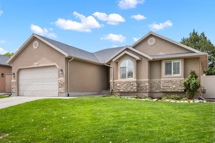 Stucco exterior with stone accent detailing, arched window, and attached garage
