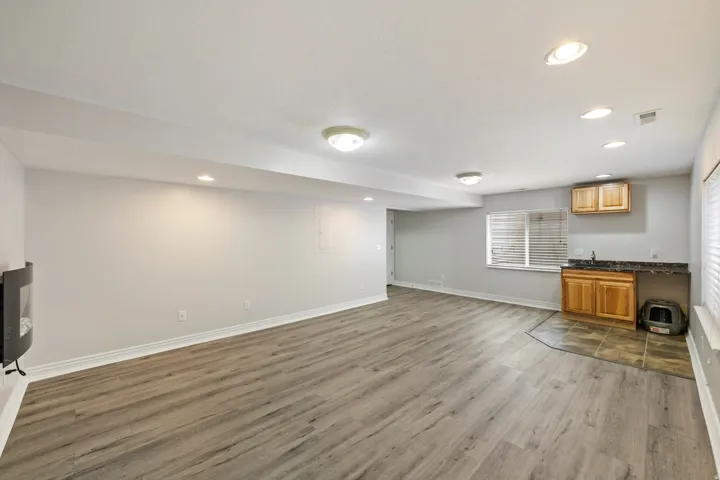 Finished basement featuring wood-finish flooring, recessed lighting, and a wet bar with wood cabinetry and dark countertops