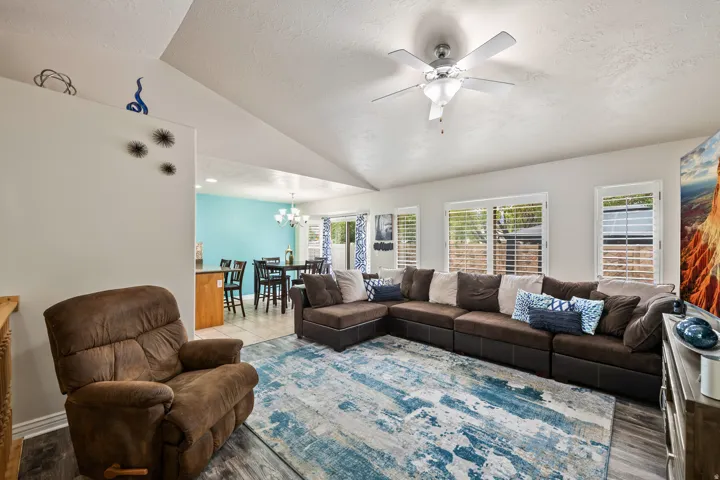 Vaulted ceiling with a ceiling fan, recessed lighting, and wood-finish flooring