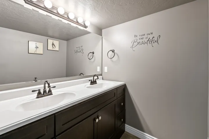 Dual vanity with integrated sinks, dark wood-finish cabinetry, brushed nickel faucets, and a full-width mirror