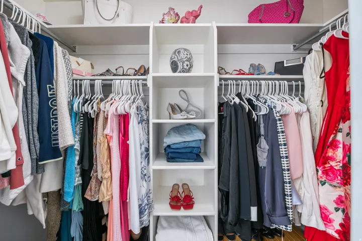 Built-in white storage system featuring multiple hanging rods, shelving, and cubbies