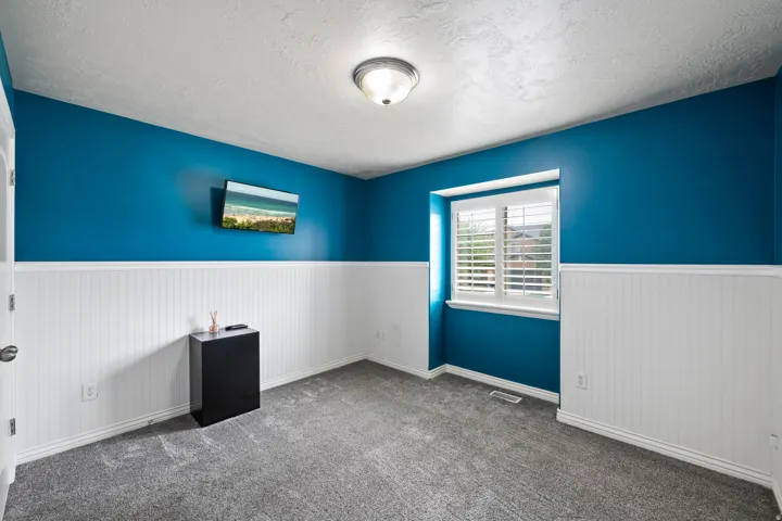 Textured ceiling, semi-flush mount ceiling light, colorful accent walls, beadboard wainscoting, and carpeted flooring