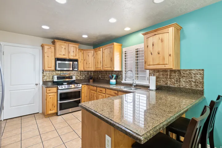 Kitchen featuring extensive wood cabinetry, stainless steel appliances, a bar-height counter, tile flooring, and recessed ceiling lighting