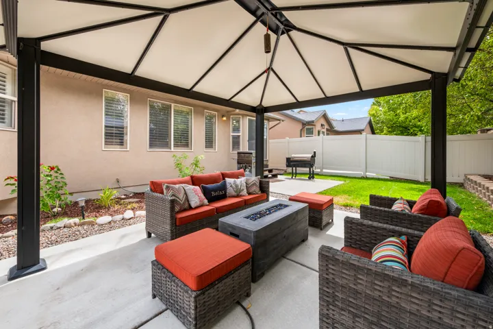 Covered patio with concrete flooring, stucco exterior, and a privacy fence