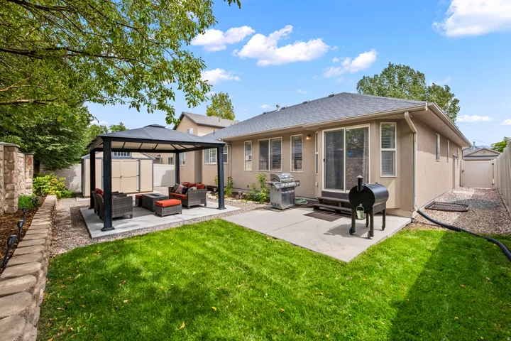Expansive backyard featuring a manicured lawn, concrete patio, and an integrated gazebo