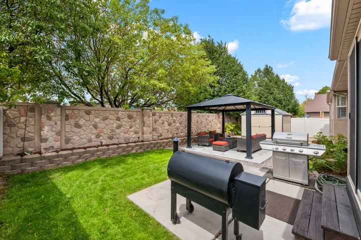 Private backyard featuring a stone and concrete privacy wall, concrete patio, and a covered gazebo structure