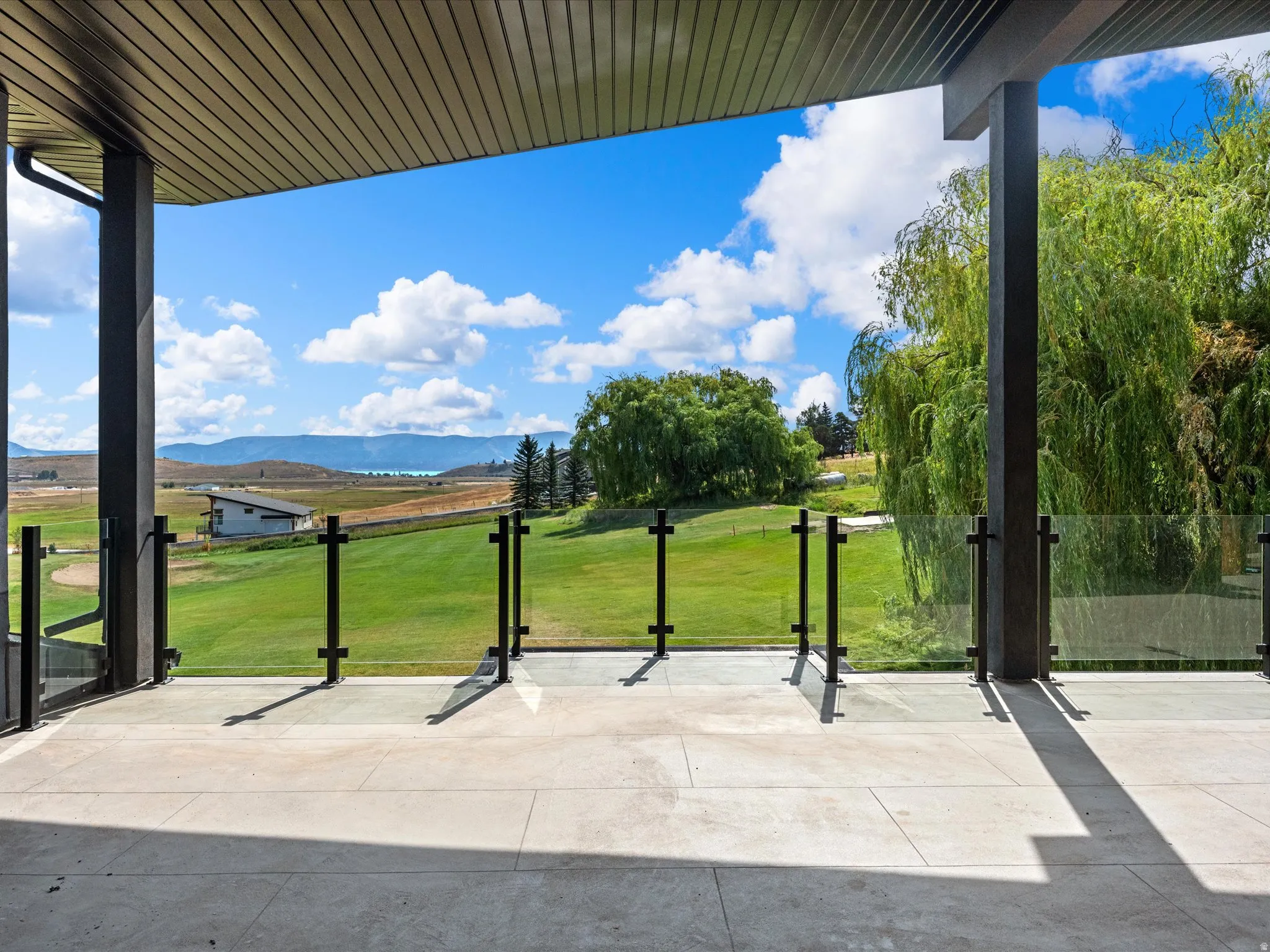 Expansive outdoor patio with glass railing and durable stone-finish flooring