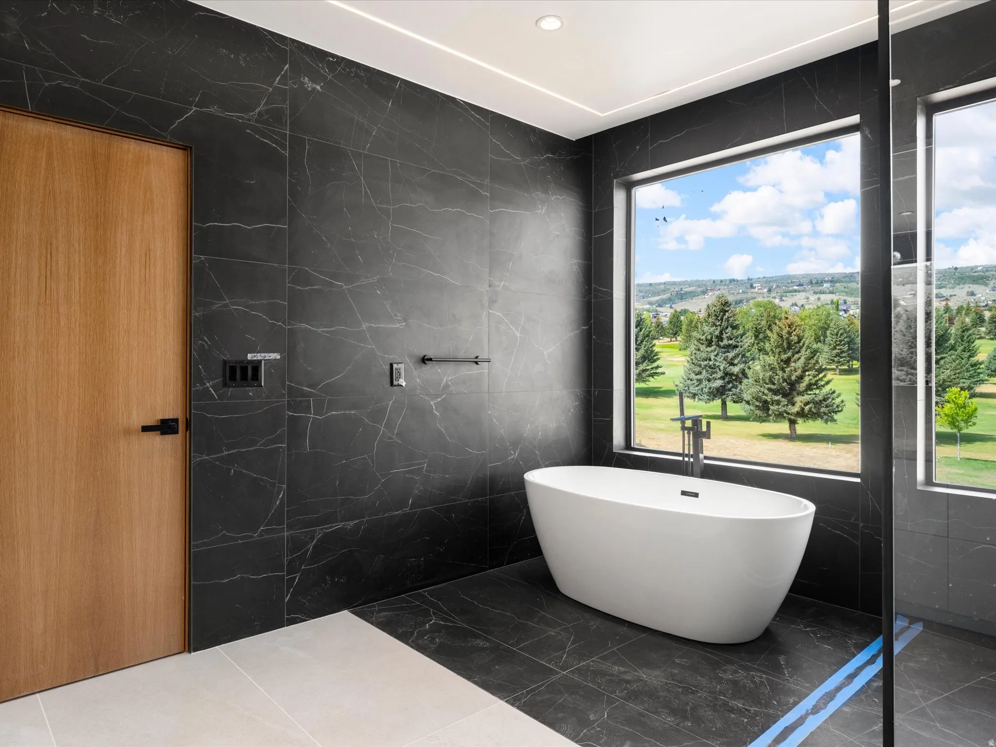 2nd Level Master En-Suite, Freestanding soaking tub, floor-mounted tub filler, and dark tiled walls