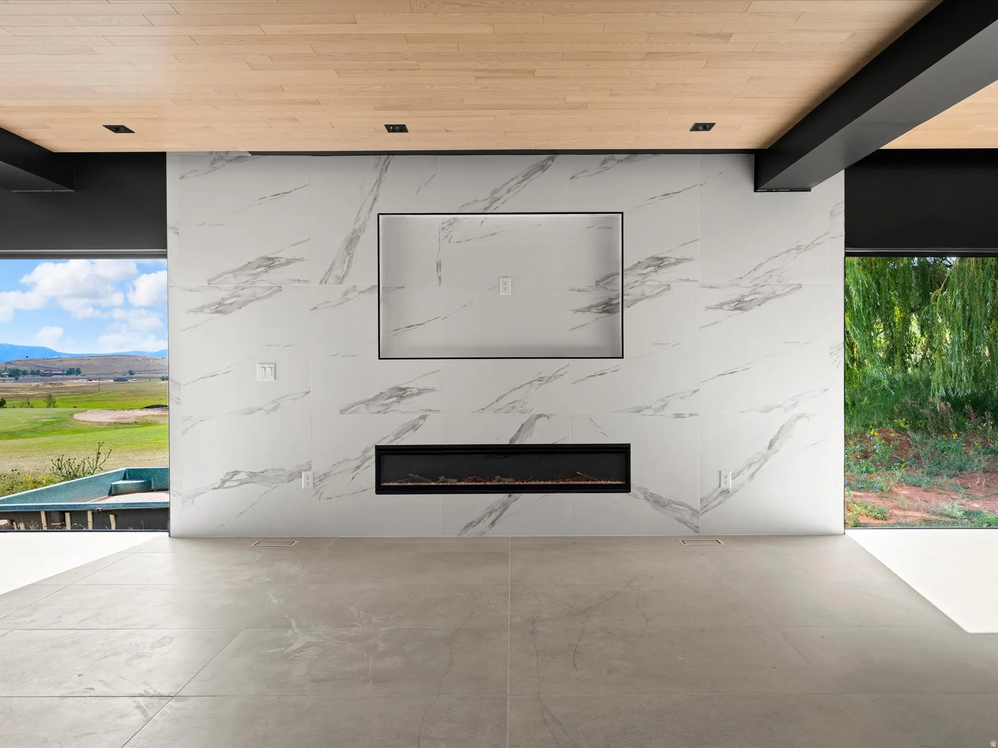 Feature wall with large format stone-look tile, integrated linear electric fireplace, and recessed television niche