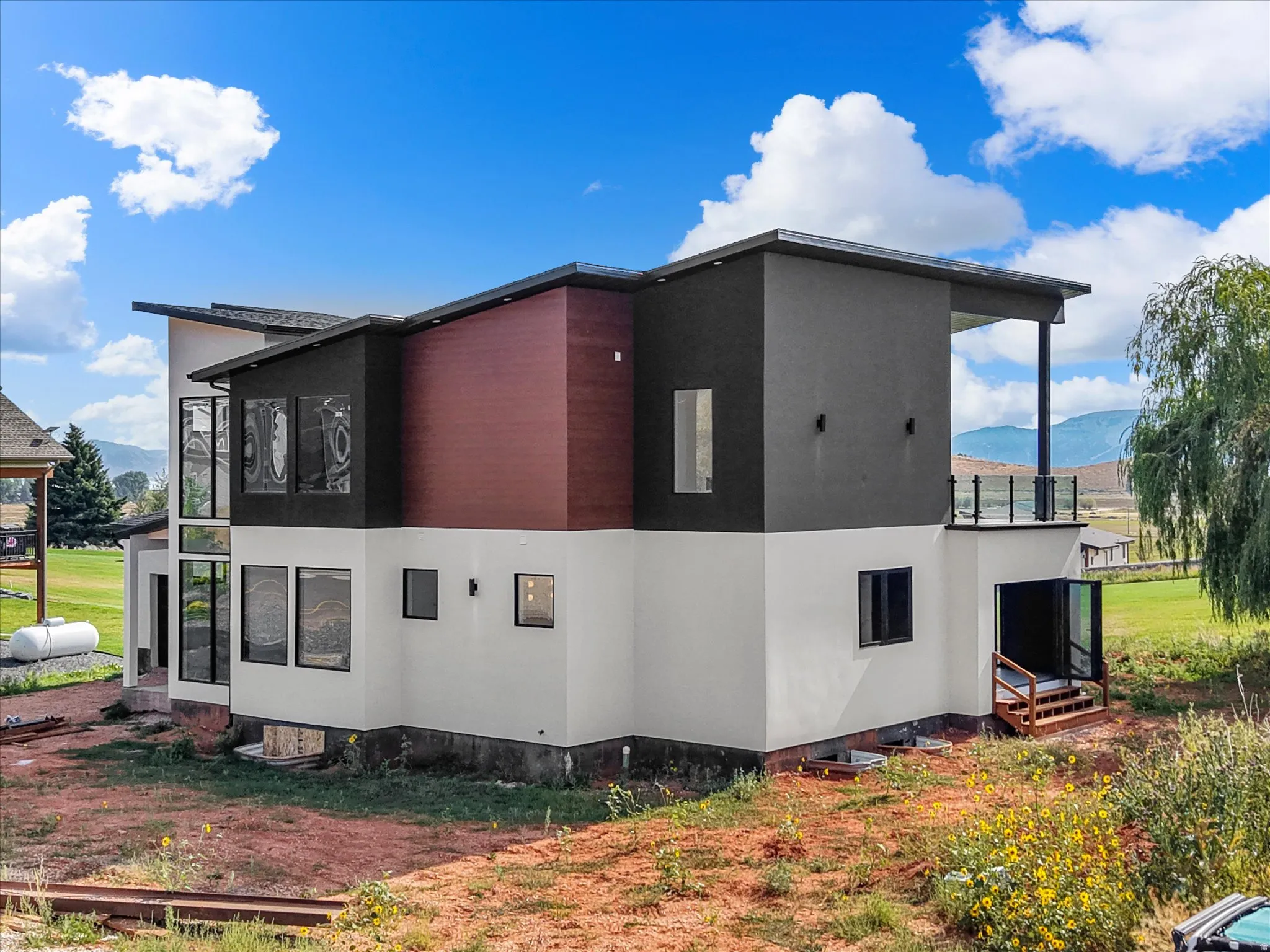 Contemporary exterior with mixed material siding, expansive windows, a second-story balcony with glass railing, and a private upper-level patio
