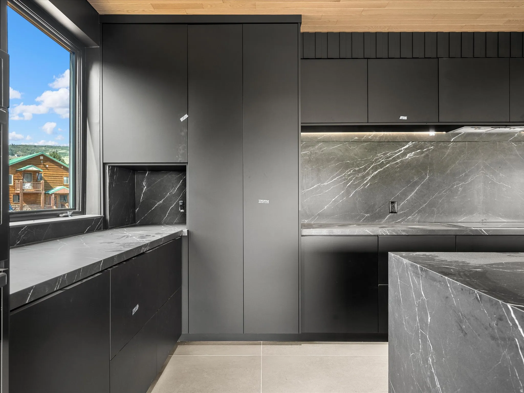Sleek kitchen featuring dark flat-panel cabinetry and a striking dark stone countertop