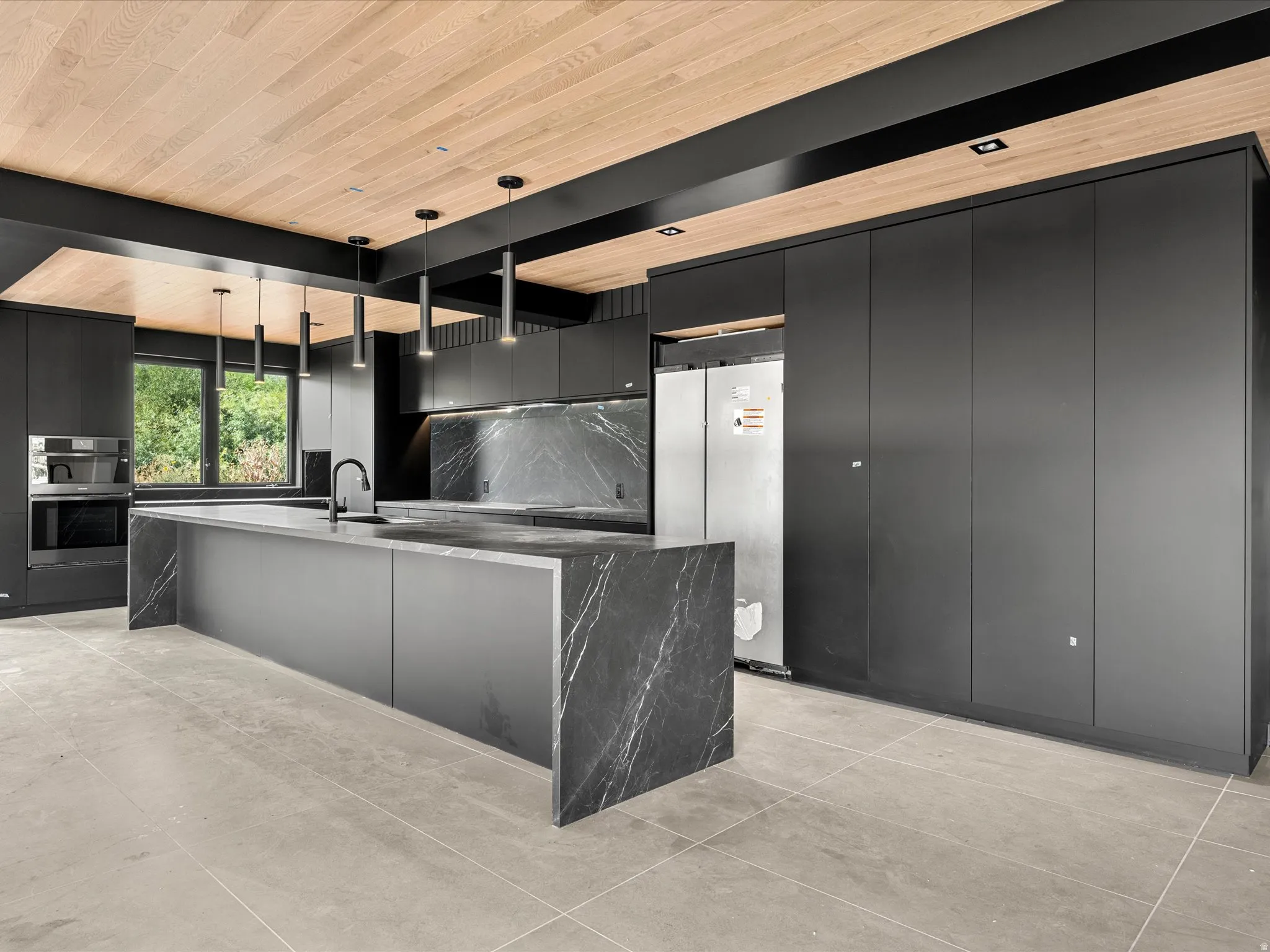 Modern kitchen with dark cabinetry, integrated appliances, a large center island with waterfall edges, and a wood-finish ceiling