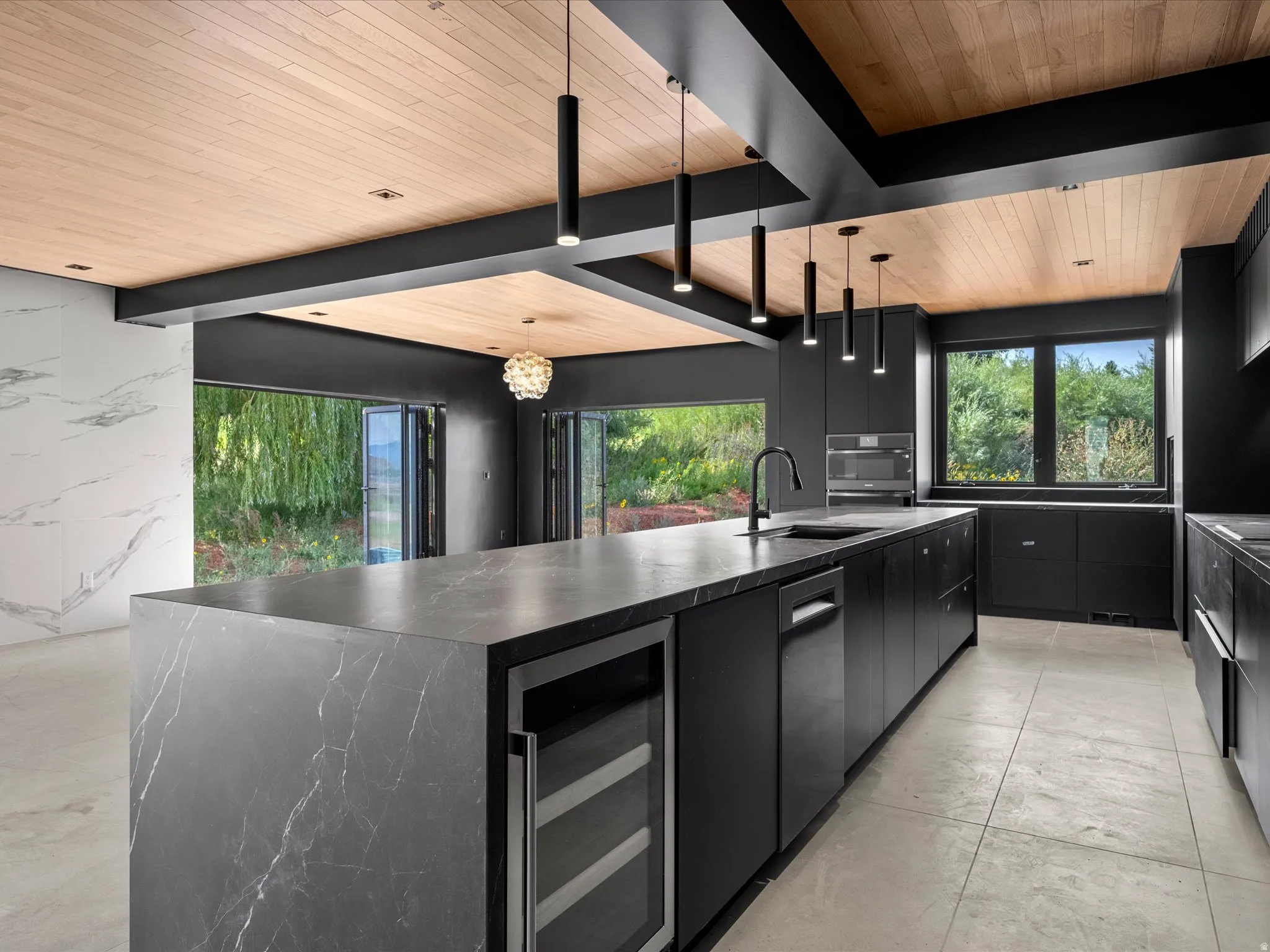 Gourmet kitchen featuring a waterfall island with integrated wine refrigeration, ceiling-mounted pendant lighting, a built-in oven, and a wood-paneled ceiling