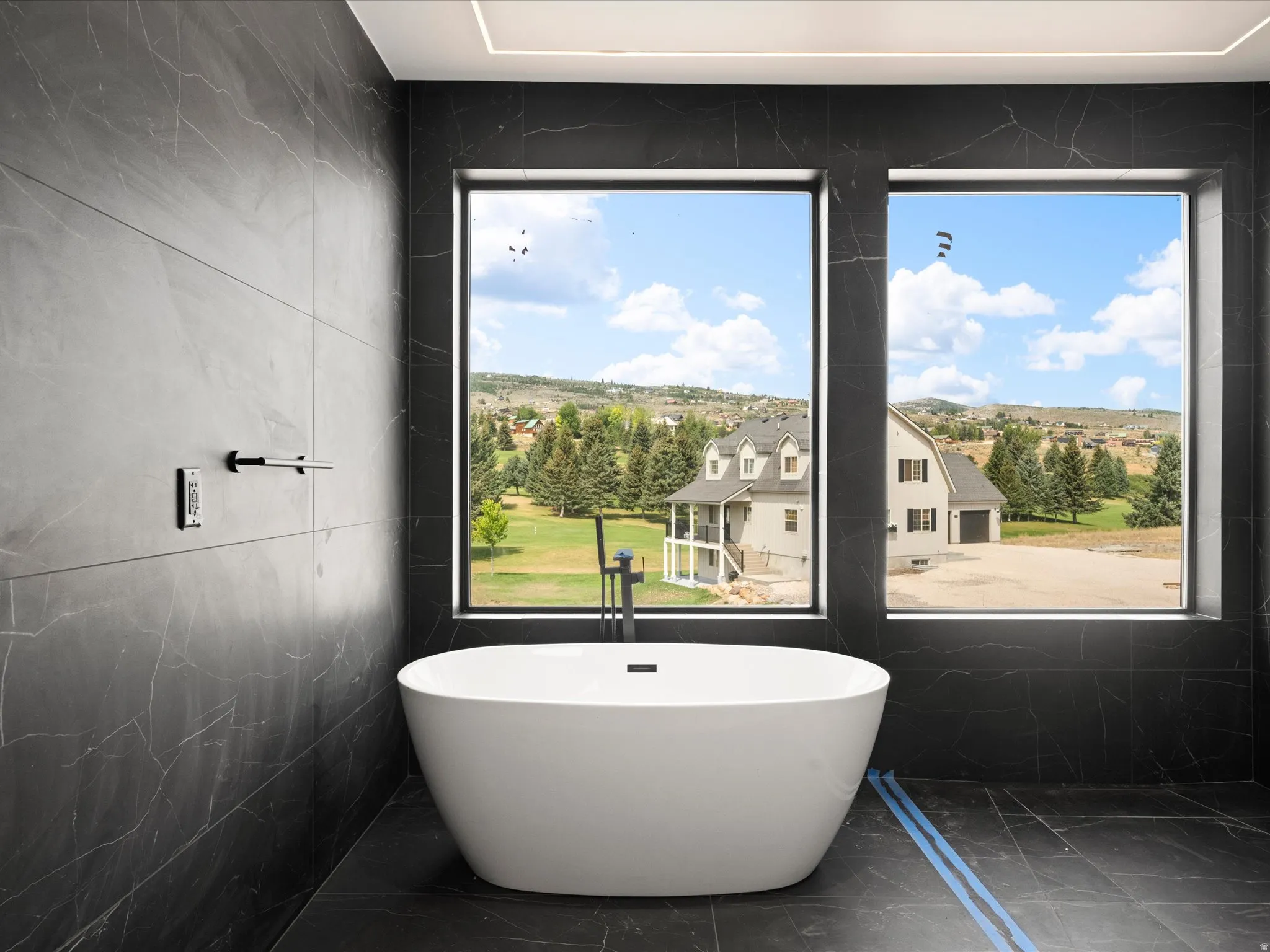 2nd Level Master En-Suite, Freestanding soaking tub with a floor-mounted faucet, complemented by large format dark tile walls and flooring