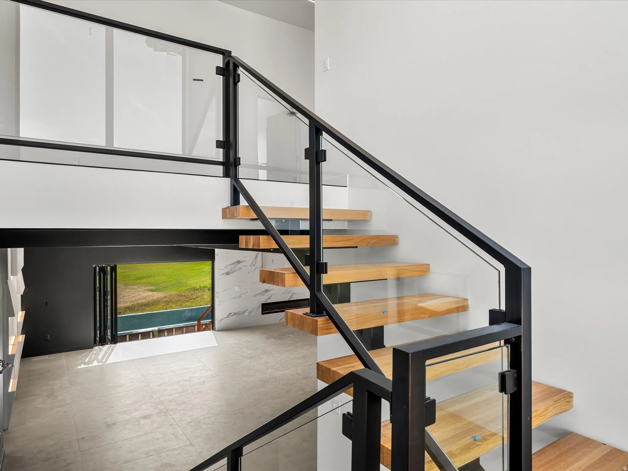Floating wood-finish staircase with glass and black metal railing