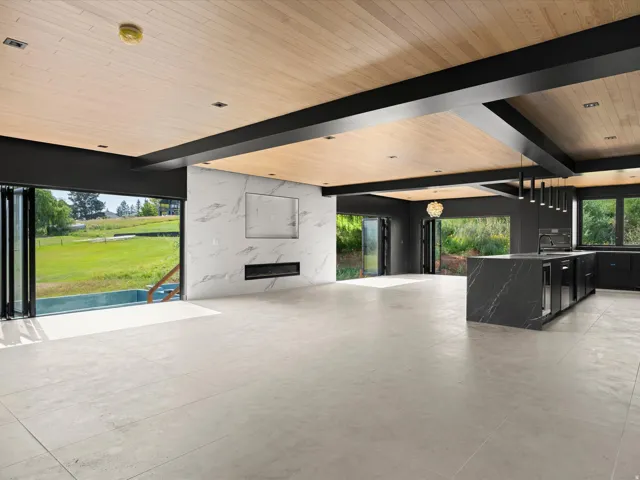 Arizona tile flooring, wood-panel ceiling, dark-finish exposed beams, fireplace with a marble-finish surround, and a dark-finish kitchen island with integrated appliances