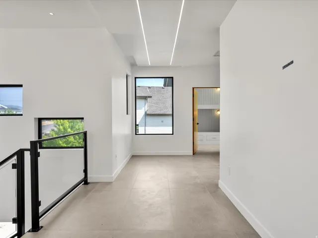 Recessed linear lighting, tile flooring, black frame windows, and a glass panel railing