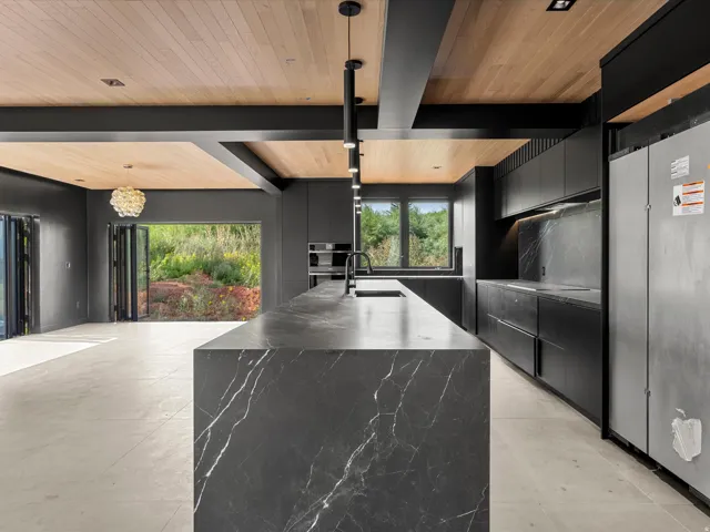 Kitchen featuring a waterfall island with a dark stone finish, integrated appliances, wood-finish ceiling, bi-fold doors, and recessed and pendant lighting