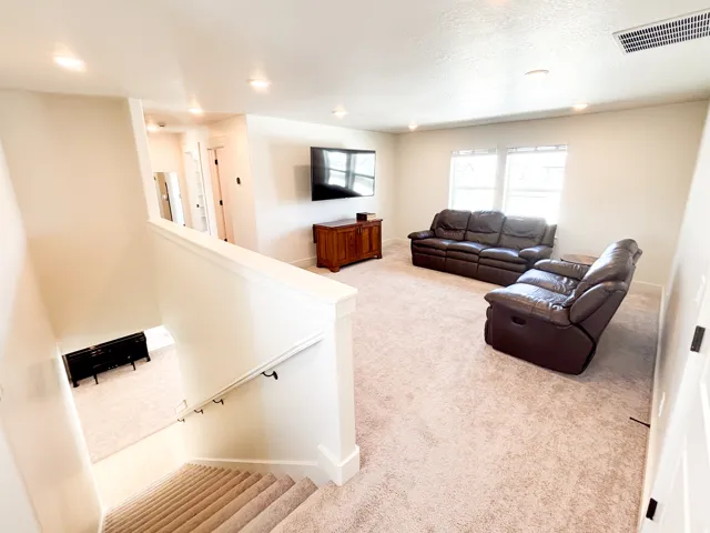 Carpeted loft space featuring recessed lighting and two windows