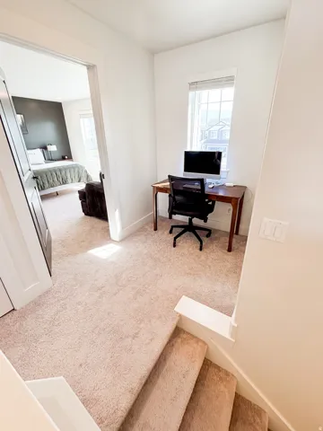 Carpeted landing with a window, white walls, and a built-in desk area