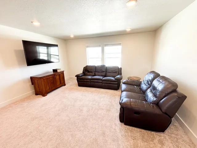 Wall-mounted television with recessed lighting and carpeted flooring