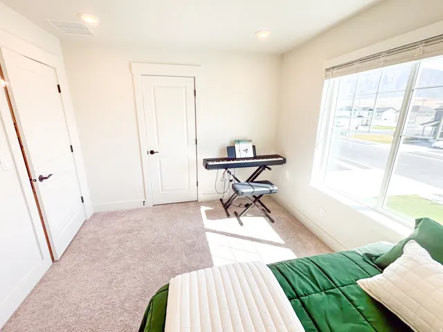 Recessed ceiling lighting, a large window with blinds, and light-colored carpet flooring