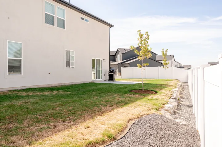 Stucco exterior with multiple windows, concrete patio, sliding glass door, and a white privacy fence