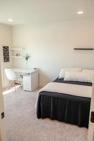 Recessed lighting illuminates neutral-toned carpeting and white walls