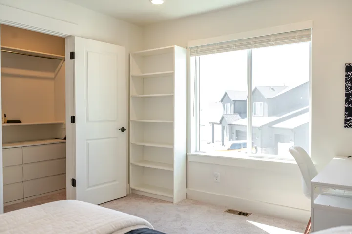 Built-in closet system with drawers, white paneled door, integrated shelving unit, and a large window