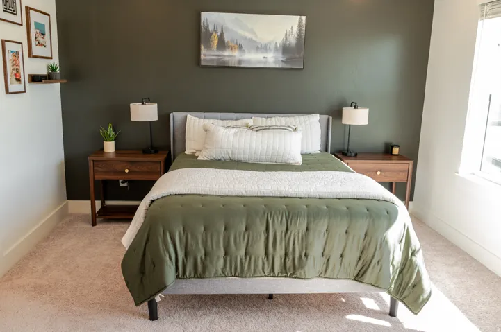 Carpeted flooring, deep green accent wall, and a large window