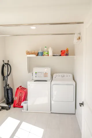 Laundry area with light-toned tile flooring, built-in shelf, and recessed lighting